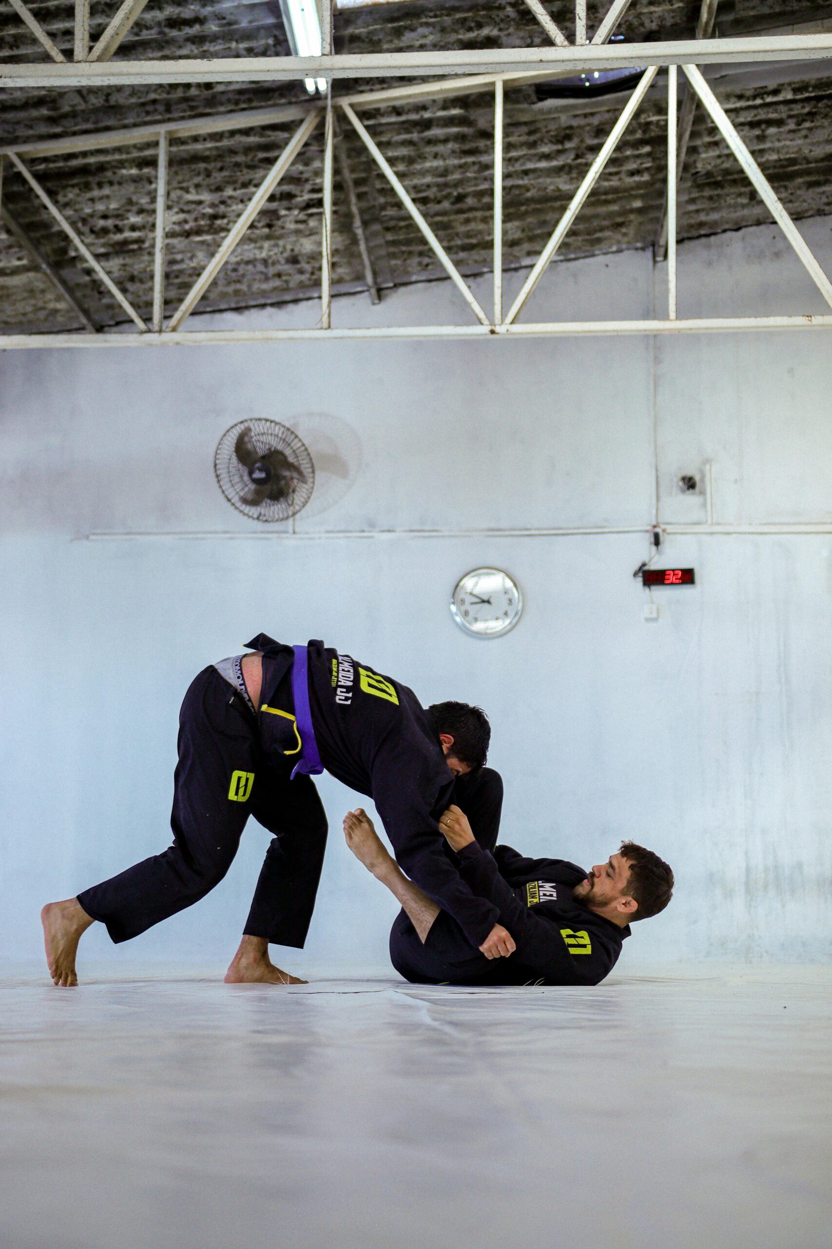 Two men practicing Brazilian Jiu-Jitsu in an indoor dojo.